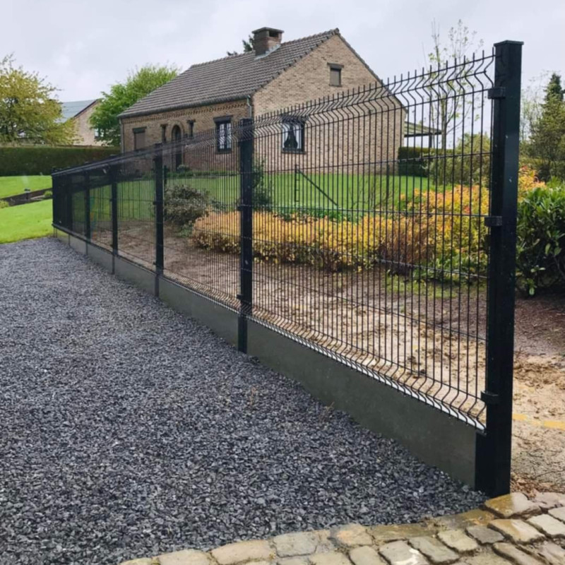 Zwarte 3D-draadpanelen met vierkante palen langs een tuin