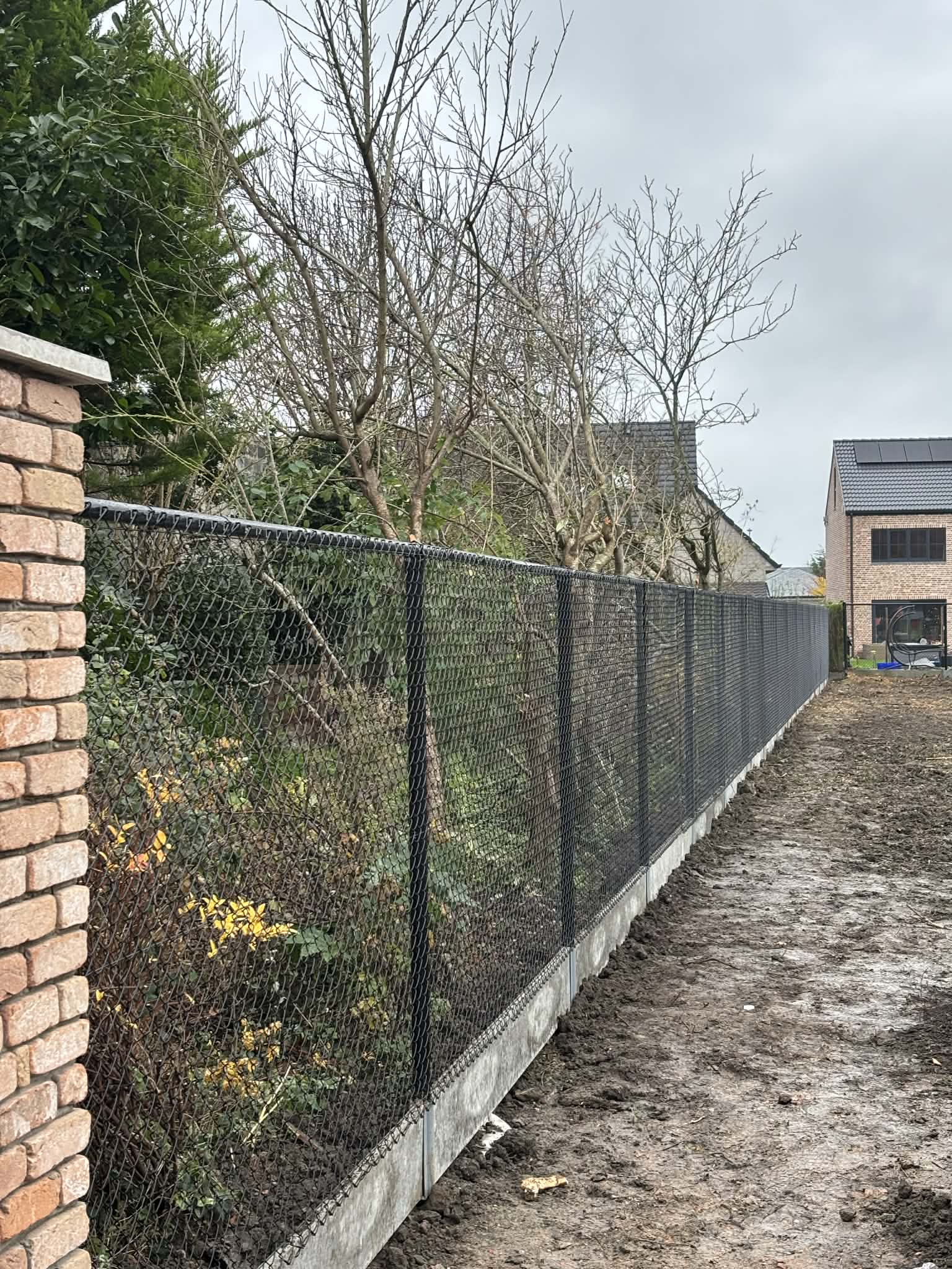 Zwarte draadafsluiting met betonplaat geplaatst door Watty Afsluitingen