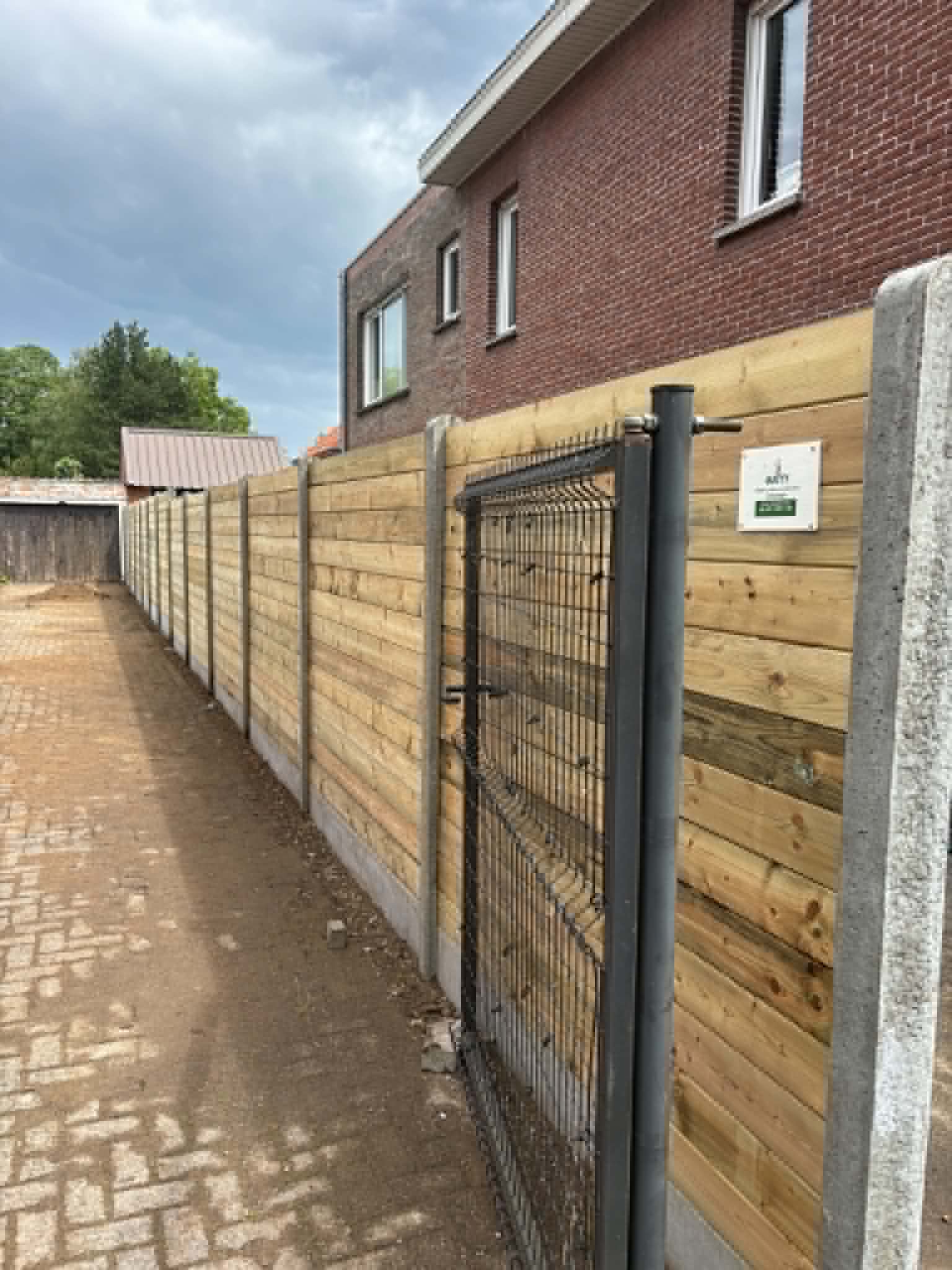Houten afsluiting met betonpalen en stalen tuinpoort