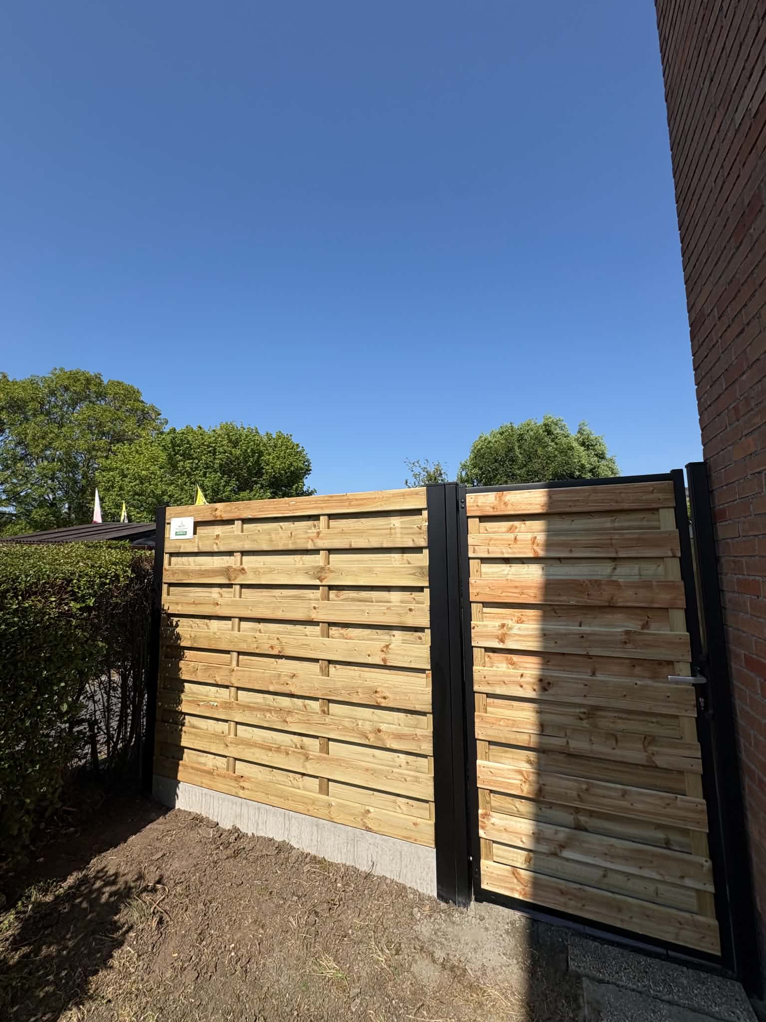 Houten schermen met zwarte palen en bijpassende tuinpoort