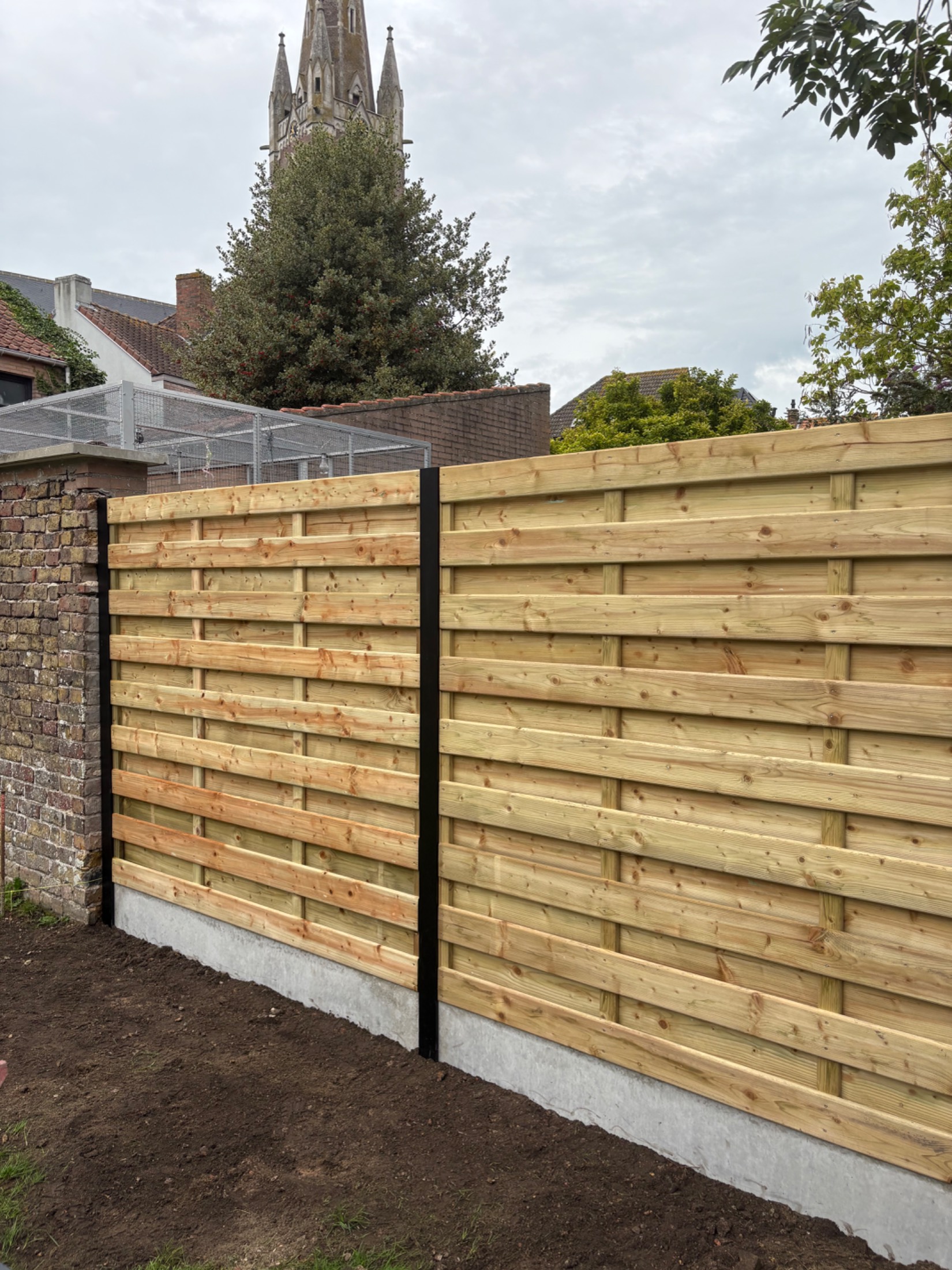 Houten scherm afsluiting met aluminium palen geplaatst door Watty Afsluitingen in Oudenburg