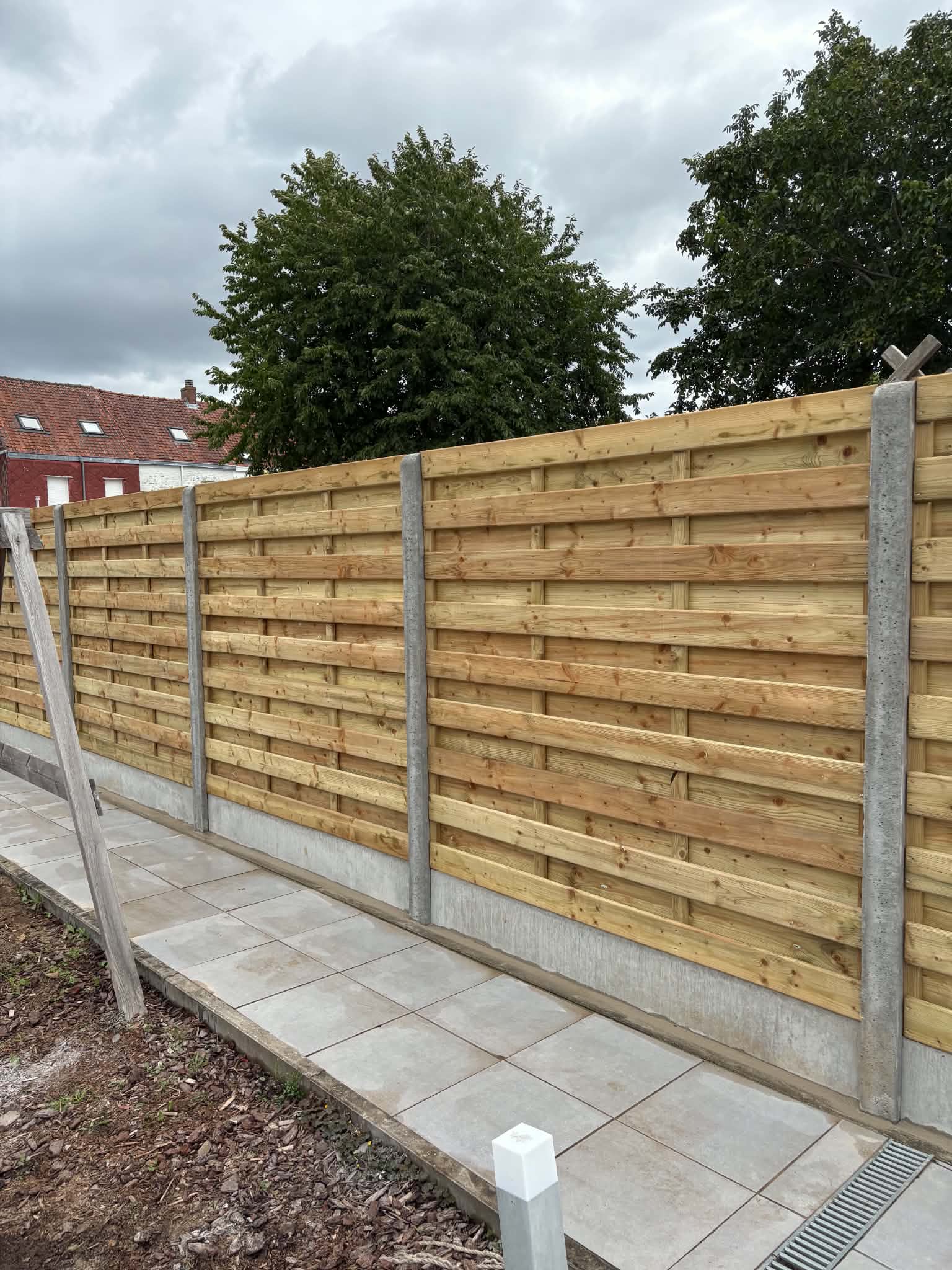 Houtenscherm afsluiting met nodige afwerking tegen onkruid geplaatst door Watty Afsluitingen in Wervik