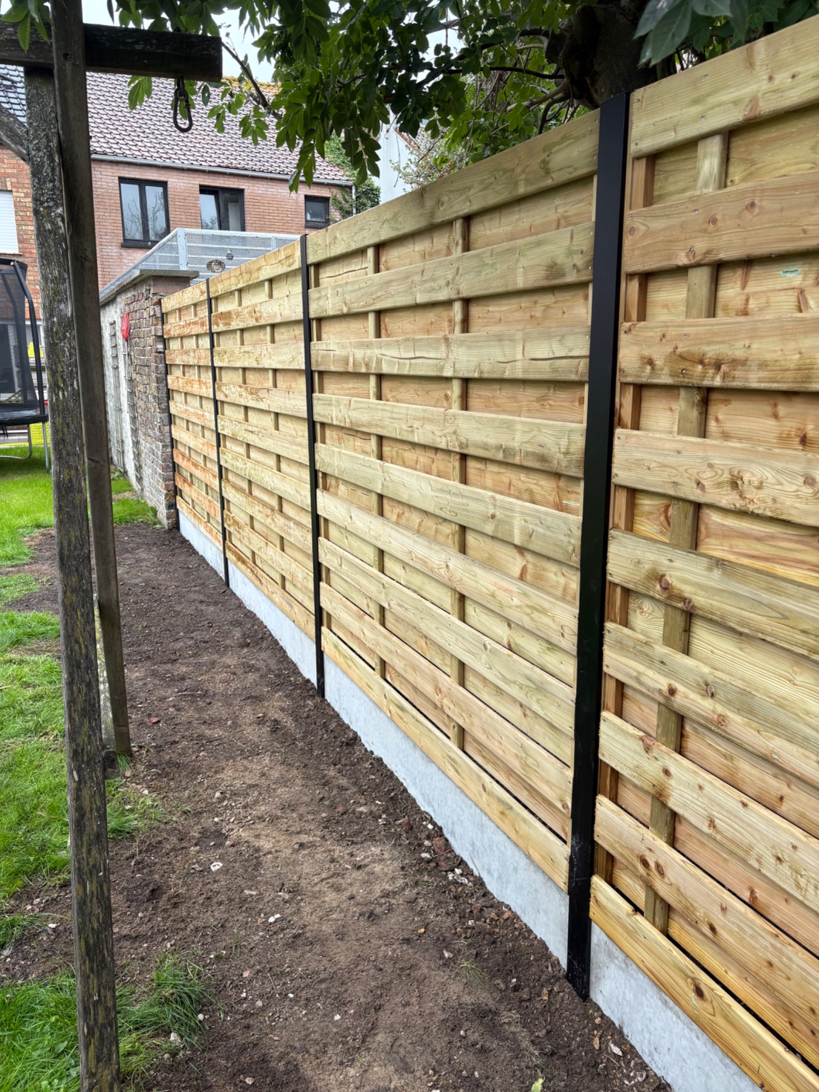 Houten scherm afsluiting met aluminium palen geplaatst door Watty Afsluitingen in Oudenburg